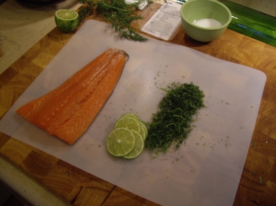 A fillet of salmon, dill, thin lime slices, and a mixture of salt and sugar.
